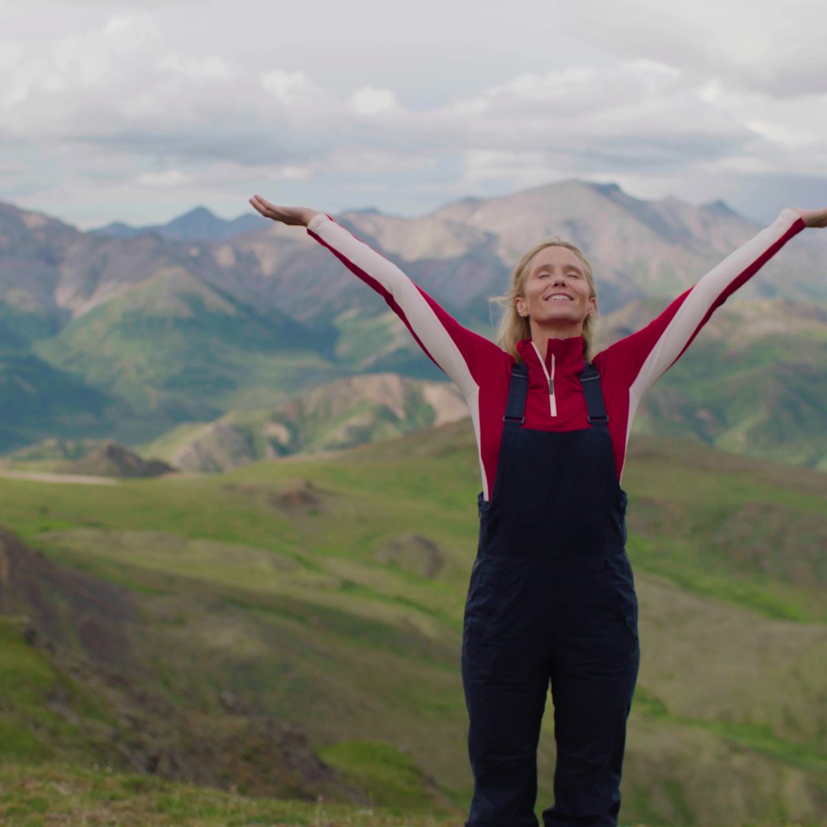A traveler with arms wide open in the Alaskan tundra